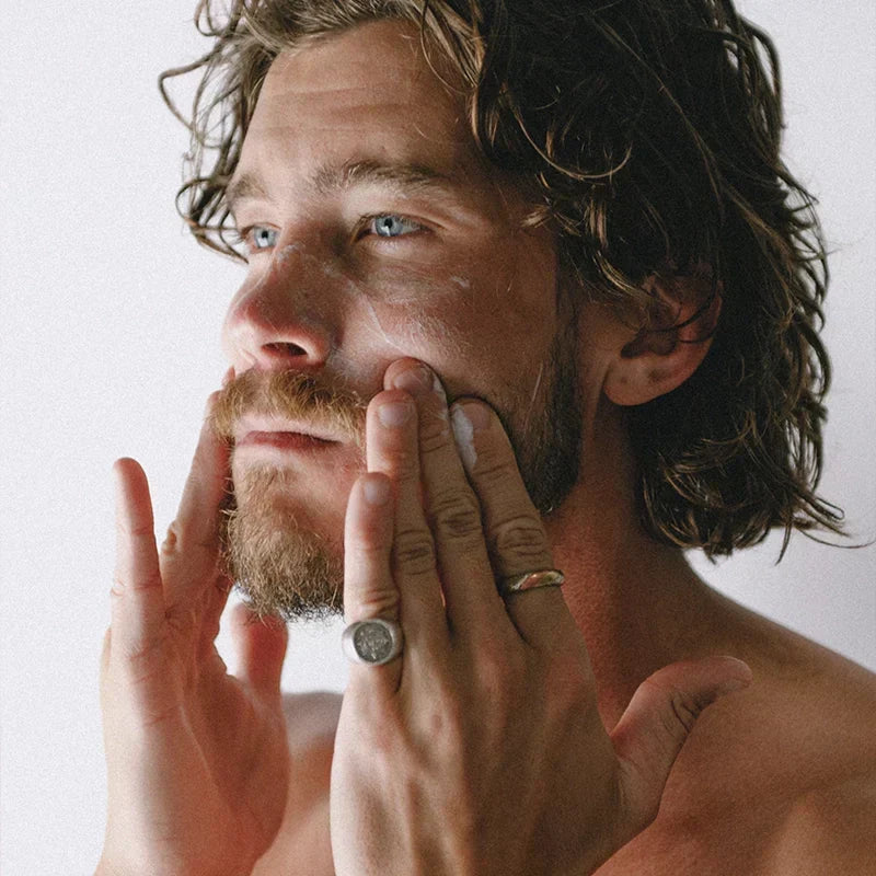 Man applying MN8 Mānuka Protect Moisturizer to face and jaw with fingertips