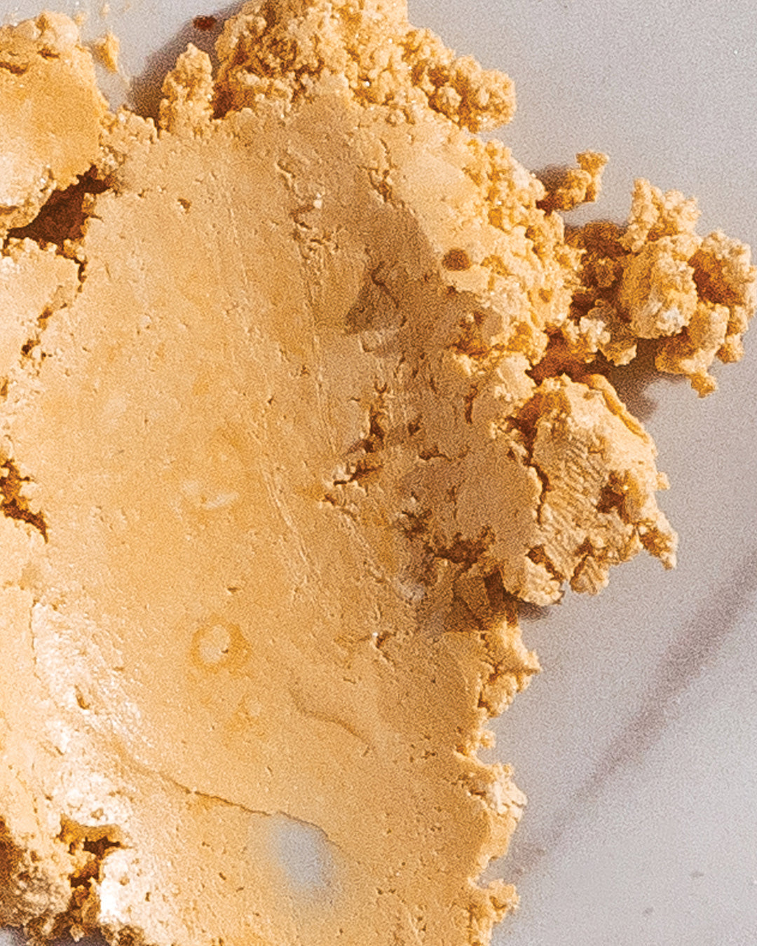 Close-up of MN8 Mānuka Gold Extract powder — golden crumbled resin texture