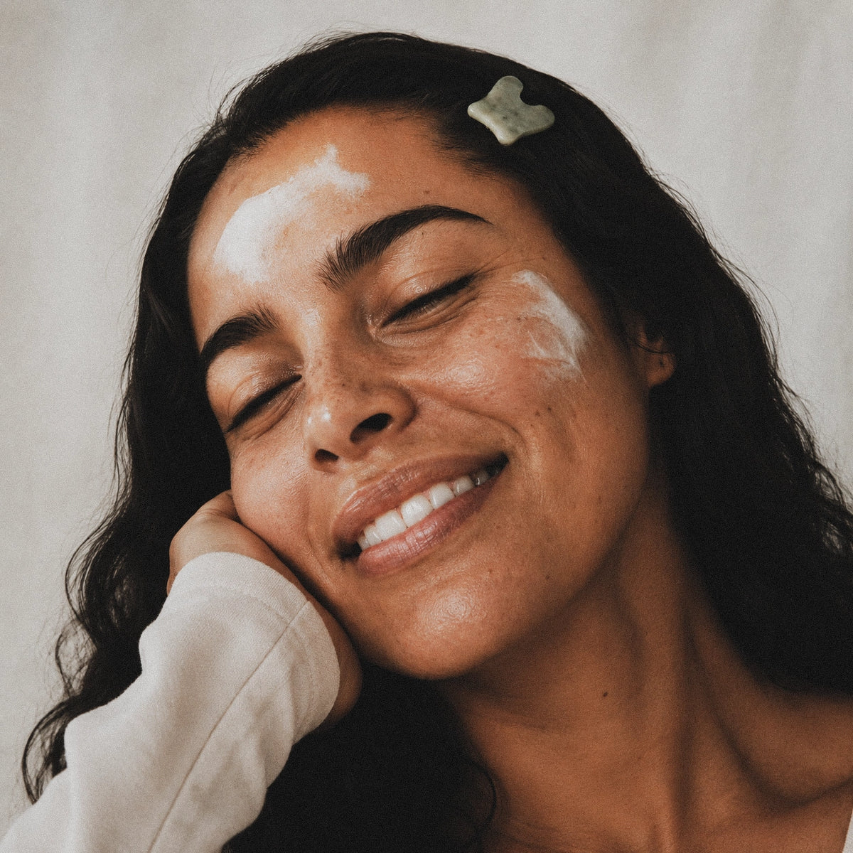 Woman with moisturizer on her face against a neutral background